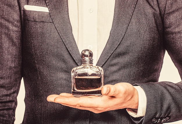 Butelka i perfumerię zapach kosmetyki butelka wody kolońskiej mężczyzna trzymający wodę kolońską Perfumy męskie Mężczyzna trzymający butelkę perfum Perfumy męskie zapach