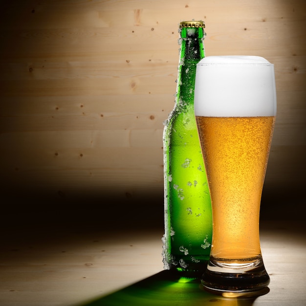 Butelka i szklanka piwa na tle drewna z lato
