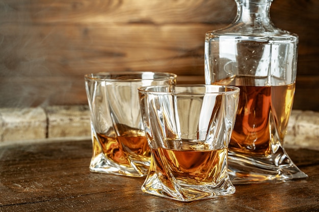 Butelka koniaku i szkła na brązowym drewnianym stole. Brandy