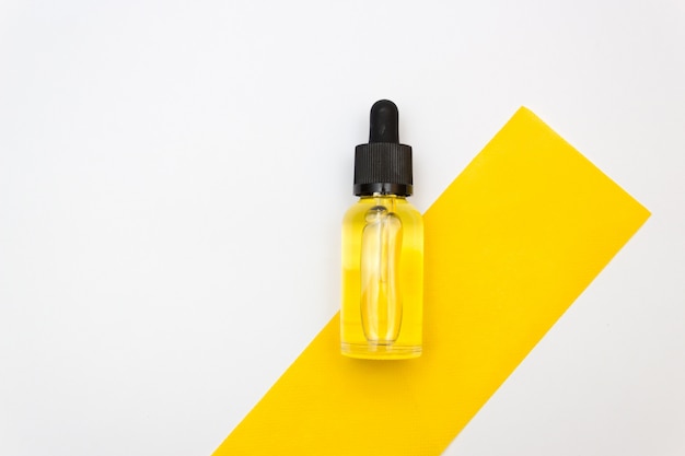 Butelka medyczna z pipetą, wypełniona przezroczystym żółtym płynem nad białym