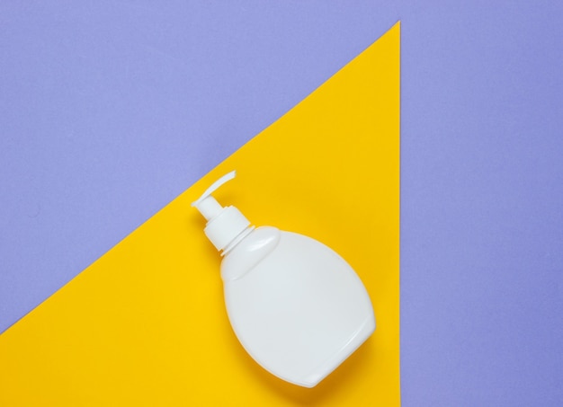 Butelka mydła w płynie na kolorowym papierze o geometrycznych kształtach