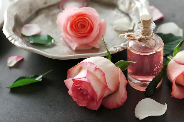 Butelka olejku aromatycznego z różami na stole