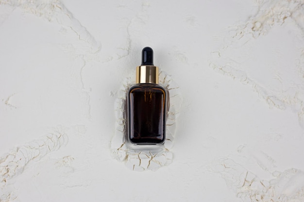 Butelka olejku kosmetycznego z serum na jasnym tle leżała płasko, widok z góry
