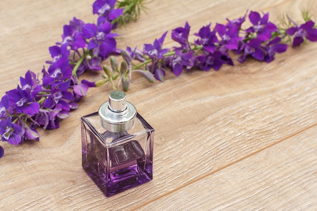 Butelka perfum i fioletowe kwiaty na drewnianych deskach