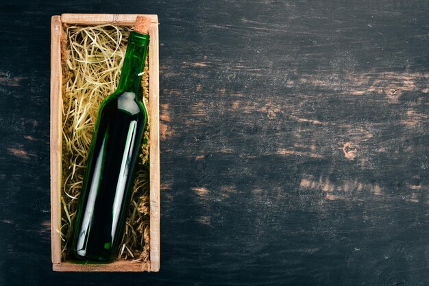 Butelka starego czerwonego wina w pudełku Na czarnym drewnianym tle Widok z góry Skopiuj miejsce na tekst