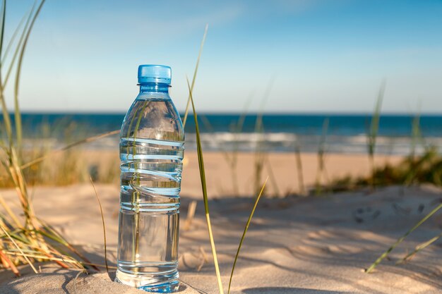 Zdjęcie butelka świeżej wody pitnej pozycja na piasku