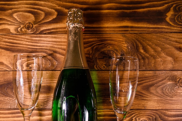 Zdjęcie butelka szampana i dwa kieliszki na rustykalnym drewnianym stole. widok z góry