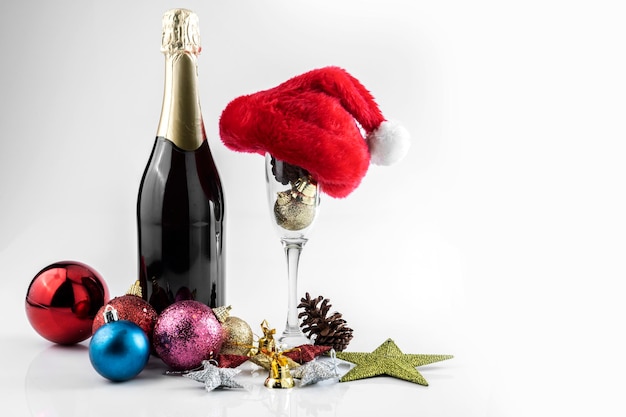 Butelka szampana z kapeluszem Mikołaja i kieliszkiem do szampana z dekoracjami świątecznymi