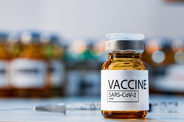 Butelka szczepionki Covid-19 ze strzykawką na stole laboratoryjnym z bliska