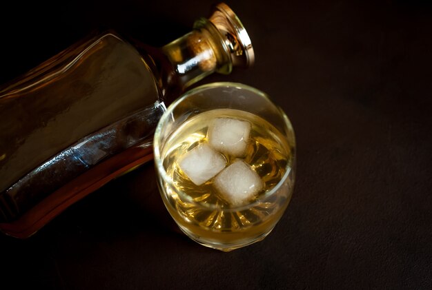 butelka whisky i szklanka whisky z lodem na betonie