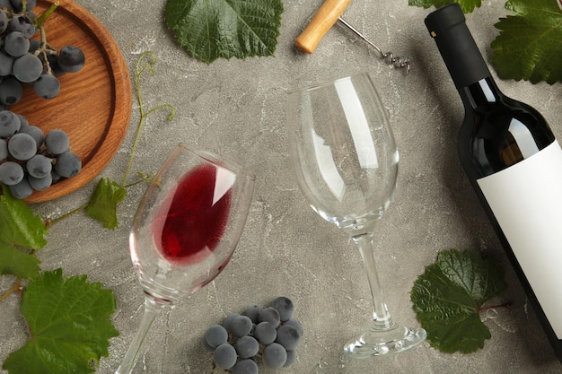 Butelka wina i kieliszek na wino z winogronami na szarym tle betonowym widok z góry