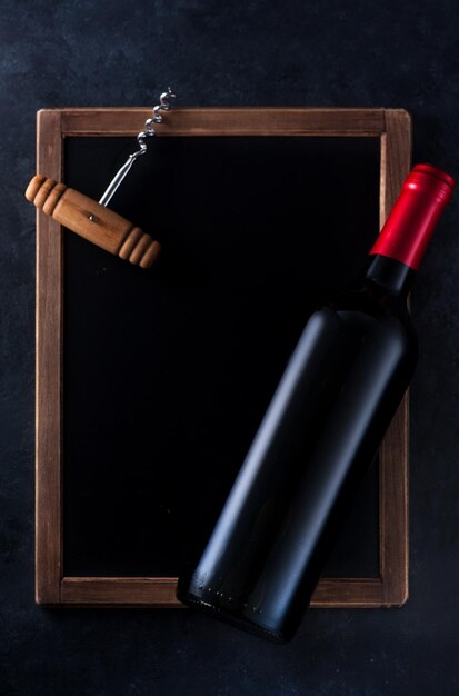 Zdjęcie butelka wina i korkociąg na tablicy z miejscem na tekst
