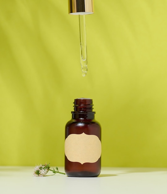 Butelka z brązowego szkła z kosmetykiem i pipetą z zielonym tłem Pojemnik na olejki