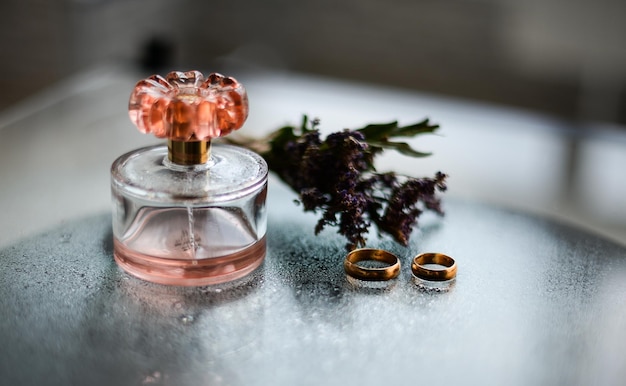 Zdjęcie butelka z perfumami i pierścienie ślubne z lawendą na szklanym stole