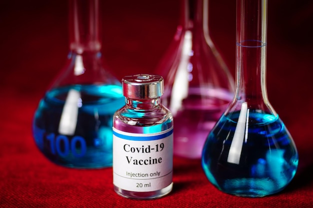 Zdjęcie butelka ze szczepionką covid19 naukowa probówka na czerwonym tleleczenie zakażenia koronawirusem