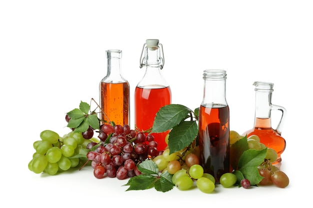 Butelki octu i winogron na białym tle