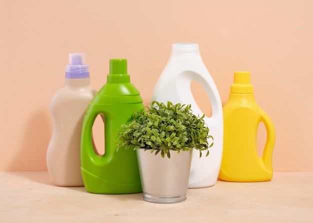 Butelki różnych kolorów z płynnymi detergentami na stole Zielona roślina w metalowym garnku