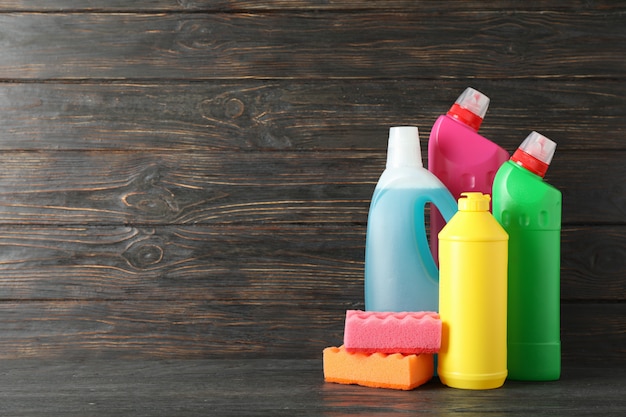Butelki z detergentem i gąbki na drewnianym tle, przestrzeń dla teksta