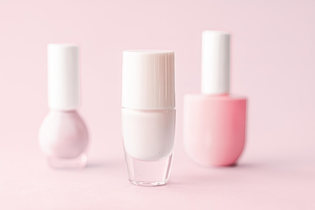 Butelki z lakierem do paznokci na różowym tle marki kosmetycznej