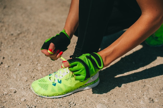 Buty do biegania - zbliżenie kobiety wiązanie sznurówki do butów. Żeński sport sprawności fizycznej biegacz dostaje przygotowywający dla jogging outdoors na lasowej ścieżce w wiośnie lub lecie.