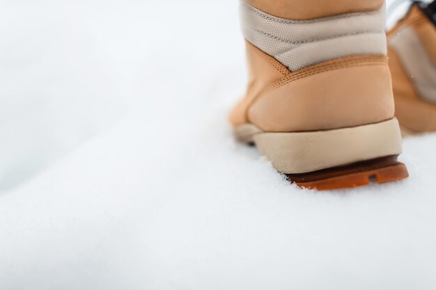 Buty męskie na śnieg. Mężczyzna w skórzanych brązowych butach spaceruje w zimowy dzień, zbliżenie