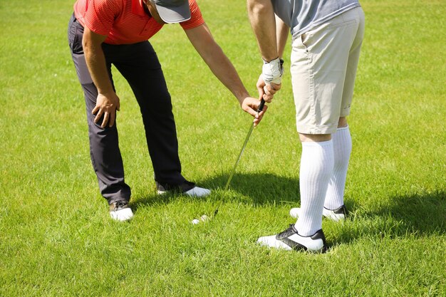 Caddy uczy młodego człowieka grać w golfa na kursie w słoneczny dzień