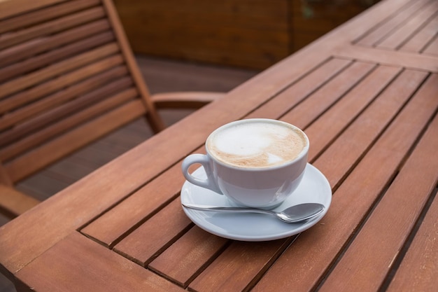 Caffe Latte Filiżanka kawy ze słodkim ciasteczkiem Dzień dobry napój Rustykalne drewniane tła BliskaŚniadanie Kawa Cappuccino sztuki na vintage drewnianym stole