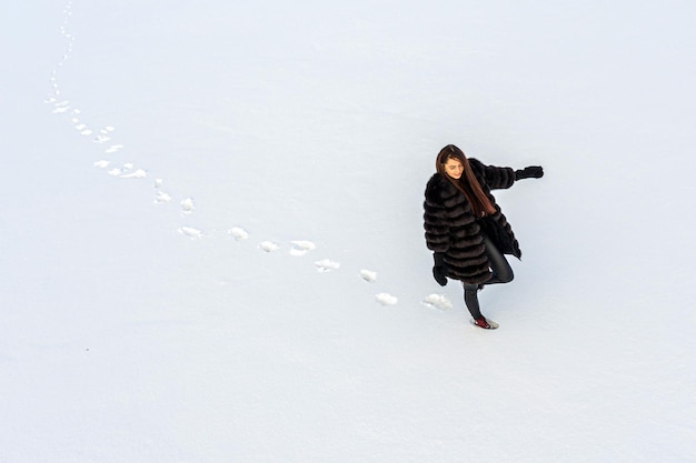 Zdjęcie cała długość kobiety idącej po śniegu