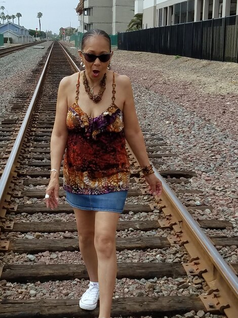 Zdjęcie cała długość kobiety idącej po torze kolejowym