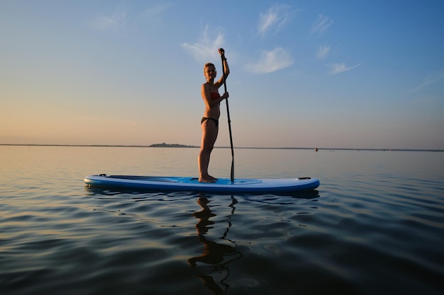 Zdjęcie cała długość kobiety paddleboarding w morzu