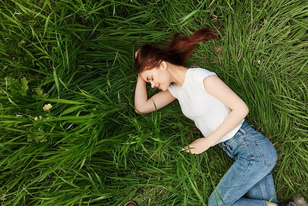 Zdjęcie cała długość młodej kobiety siedzącej na trawiastym polu