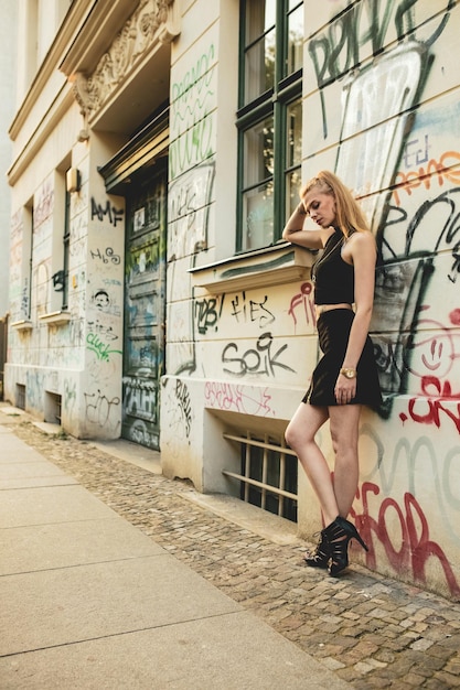 Zdjęcie cała długość młodej kobiety stojącej przy ścianie graffiti