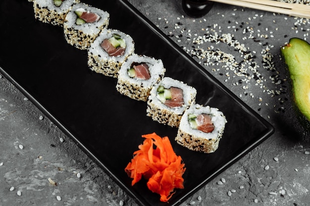 California roll sushi tradycyjne japońskie jedzenie ryżowe z łososiem, awokado, ogórkiem, nori i sezamem.