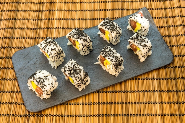 Zdjęcie california roll sushi uramaki z czerwonym tuńczykiem mango i awokado nori wodorosty czerwony tuńczyk sezam serek śmietankowy i imbir z wasabi