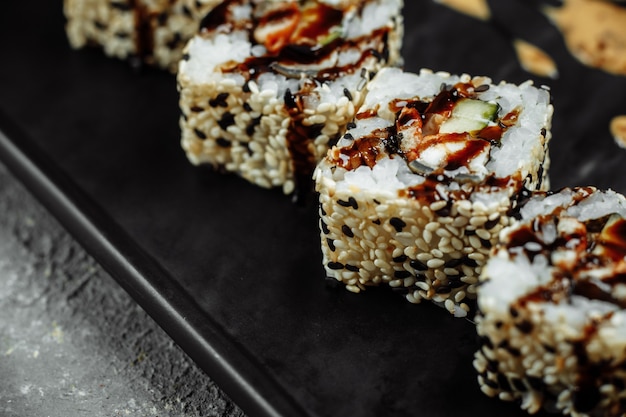 Zdjęcie california roll sushi z wędzonym węgorzem, ogórkiem, awokado. menu sushi. japońskie jedzenie.