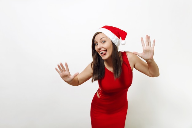 Całkiem kaukaski młoda szczęśliwa kobieta z uroczym uśmiechem na sobie czerwoną sukienkę i świąteczny kapelusz rozłożone ręce na białym tle. Santa dziewczyna. Święto Nowego Roku 2018. Skopiuj miejsce na reklamę