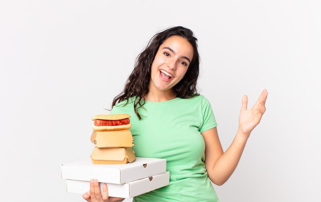 Całkiem latynoska kobieta czuje się szczęśliwa, zaskoczona, gdy zdaje sobie sprawę z rozwiązania lub pomysłu i trzyma na wynos pudełka z fast foodami