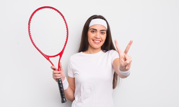 Całkiem latynoska kobieta uśmiechnięta i patrząca przyjaźnie, pokazując numer dwa. koncepcja tenisa