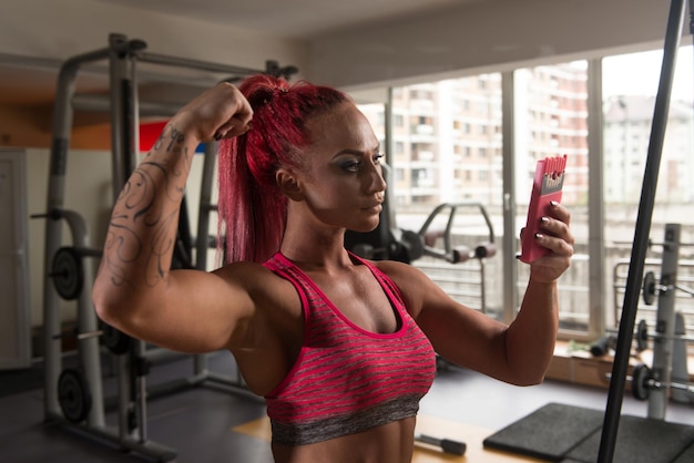 Całkiem mieszana rasa kobieta robi selfie w siłowni w centrum fitness w tle