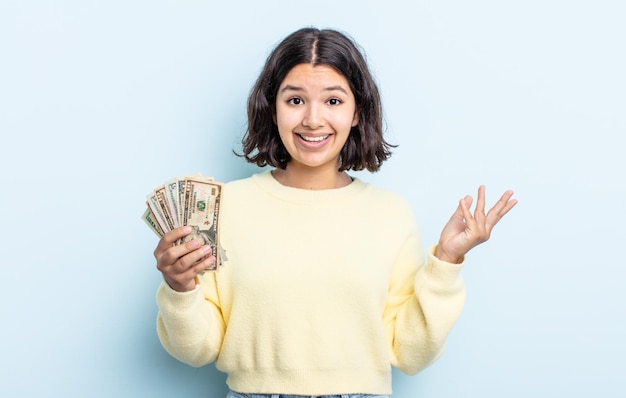 Całkiem młoda kobieta czuje się szczęśliwa, zaskoczona, gdy zdaje sobie sprawę z rozwiązania lub pomysłu. koncepcja banknotów dolarowych