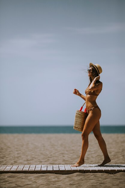 Całkiem Młoda Kobieta W Bikini Spacerująca Po Plaży W Lecie