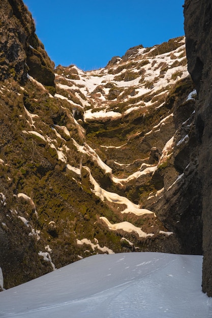 Całkowicie śnieżna droga między górami w kierunku wodospadu Kvernufoss i wąwozu ze śniegiem