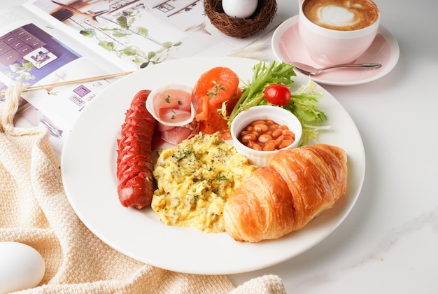 Całodzienne śniadanie z grzanką fasolową croissanty chińska kiełbasa sos jajko i latte podawane w naczyniu odizolowanym na stole widok angielskie śniadanie