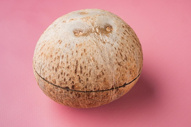 Cały dojrzały świeży kokos na różowym teksturowanym letnim tle