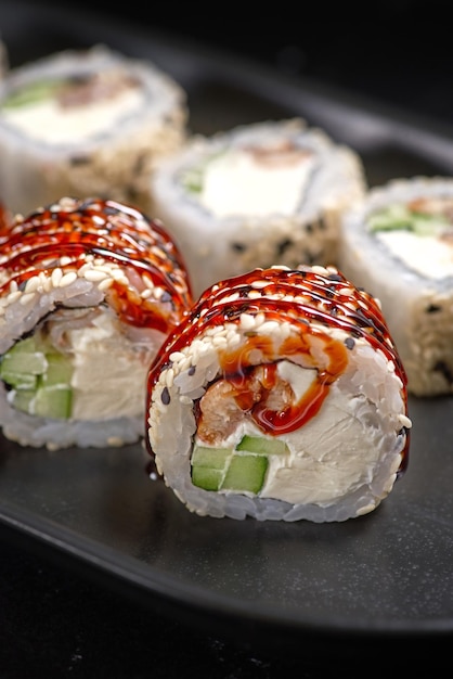 Canada Roll z kremem z węgorza i ogórkiem umieszczonym na czarnym teksturowanym tle Menu sushi Japońskie jedzenie