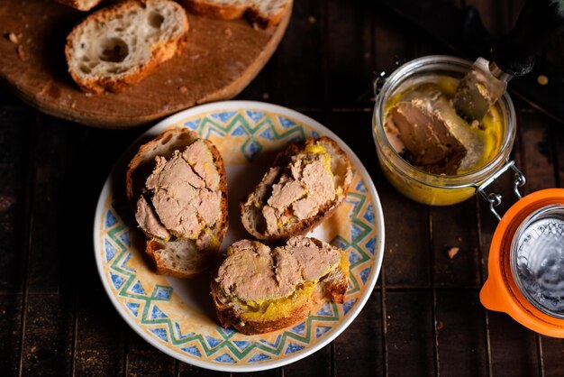 Canape bruschetta z foie gras Bagietka z maślaną gęsią wątróbką na półmisku na ciemnym tle