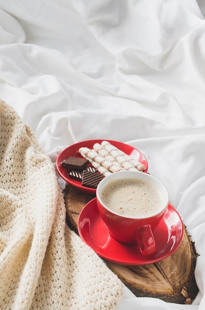 Cappuccino i czekolada na łóżku z plaid.