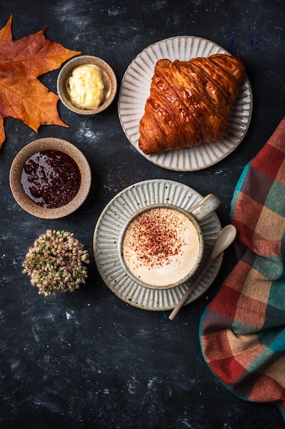 Cappuccino kawa z croissant na stole, jesieni śniadaniowy pojęcie, odgórny widok