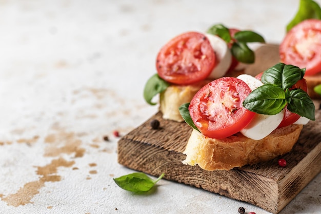 Caprese bruschetta z pomidorową mozzarellą i bazylią na drewnianej desce Spacja na tekst