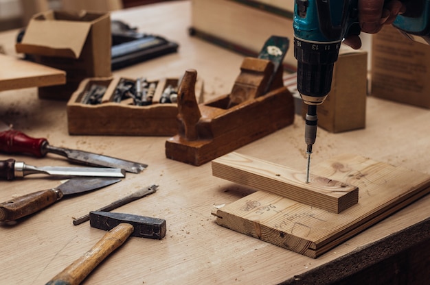 Carpenter wierci otwór wiertarką elektryczną